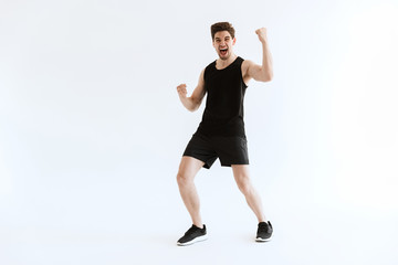 Wall Mural - Strong young sports man running isolated over white wall background make winner gesture.