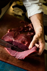 Canvas Print - man cutting a piece of beef in a professional kitchen