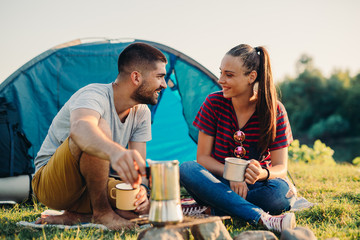 Wall Mural - young couple on camping by the river drinking tea or coffee