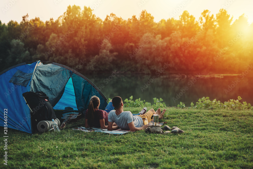young couple relaxing by the river. camping outdoor - obrazy, fototapety, plakaty 