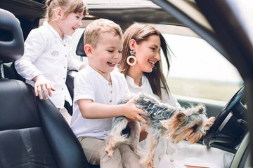 Mother with two children and a dog traveling by car