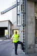 © cherryandbees - worker in safety equipment climbing on industrial ladders