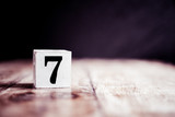 Fototapeta  - Number 7 isolated on dark background- 3D number seven isolated on vintage wooden table