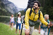 © NDABCREATIVITY - Group of smiling friends hiking with backpacks outdoors. Travel, tourism, hike and people concept.