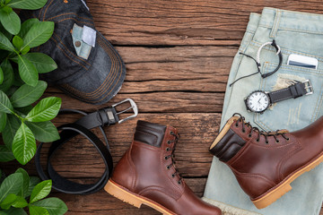 Wall Mural - Men's accessories and essential travel items with space for text or object on rustic wooden background. All leather include brown boots, belt, phone, hat, sunglass, short and watch. Flat lay, top view