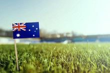Miniature Stick Australia Flag On Green Grass, Close Up Sunny Field. Stadium Background, Copy Space For Text.