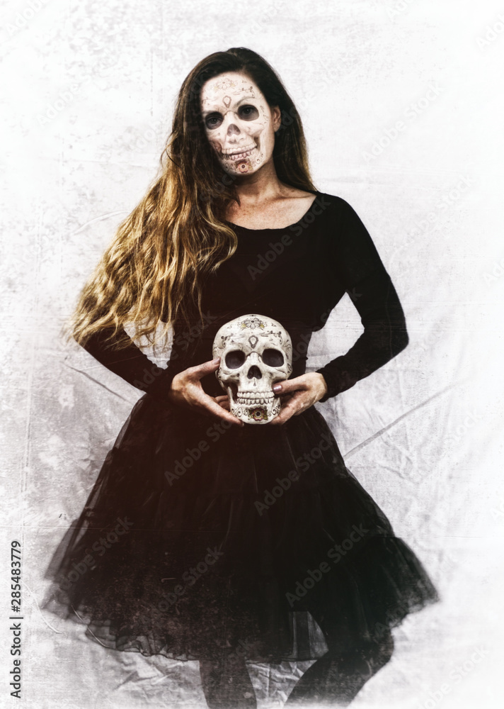 Woman in a black dress and skeleton day of the dead facial features,  holding a skull. Edited with vintage film effects. Stock Photo | Adobe Stock