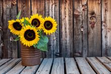 A Rusty Can Filled With A Bouquet Of Sunflowers On A Rustic Wooden Plank Table With Space For Copy.