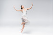 © LIGHTFIELD STUDIOS - young elegant ballerina in white dress dancing on grey background