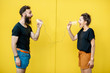 © rh2010 - Man and woman talking with string phone, shouting on each other on the yellow background. Concept of communication and misunderstanding