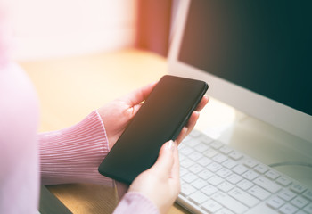 business woman holding the device digital smartphone on office desk with personal computer for social network technology communication concept