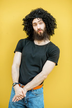 Portrait Of A Weird Man With Curley Black Hair Standing On The Yellow Background