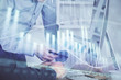 © peshkova - Double exposure of chart with businessman typing on computer in office on background. Concept of hard work.