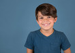 © ShannonK - Handsome happy smiling boy in blue shirt isolated on blue background