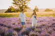 Love Couple in Lavender Field Spend Romantic Time. Beautiful Happy People Walking Together Outdoor. Woman Hold Flower Bouquet. Caucasian Man and Girl on Purple Blooming Meadow Front View
