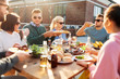 © Syda Productions - leisure and people concept - happy friends eating and drinking at barbecue party on rooftop