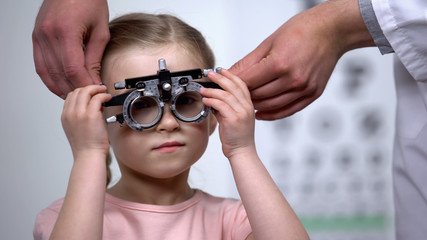 Canvas Print - Doctor wearing at adorable child eye testing glasses to diagnose vision problems