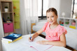 © Syda Productions - children, education and learning concept - student girl with book writing to notebook at home