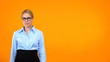 Confident woman in suit and eyeglasses on orange background, business coach