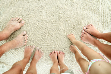 Family feet on the sand on the beach