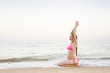 © somemeans - Young pregnant woman is practicing yoga sitting on the sea beach. Summer day