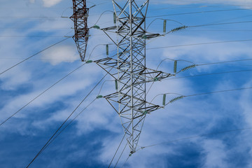 Supports high-voltage power lines against the blue sky with clouds. Electrical industry