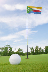 Wall Mural - The Comoros flag on golf course putting green with a ball near the hole