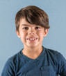 © ShannonK - Smiling young boy with big grown up teeth isolated on blue background