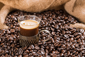 Coffee cup and coffee beans on a wooden table and sack background