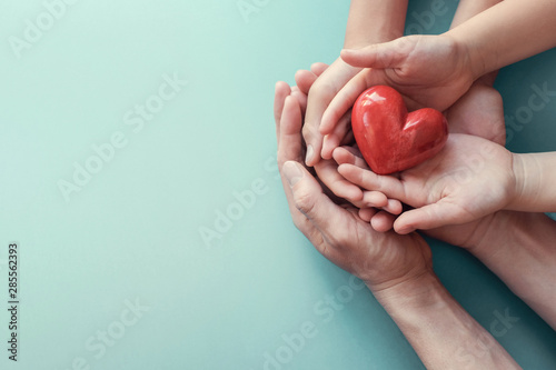 Fotomural adult and child hands holding red heart on aqua background, heart health, charit