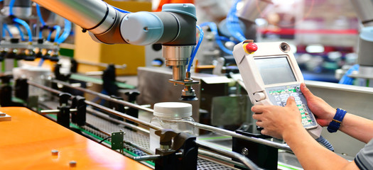 Engineer check and control automation robot arms arranged glass water bottle on Automatic industrial machinery equipment in production line factory