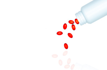 Poster - Pour red soft gel capsule pills out of drug bottle isolated on white background. Red soft gelatin capsule vitamins and dietary supplements. Pharmaceutical industry. Pharmacy drug store. Healthcare.