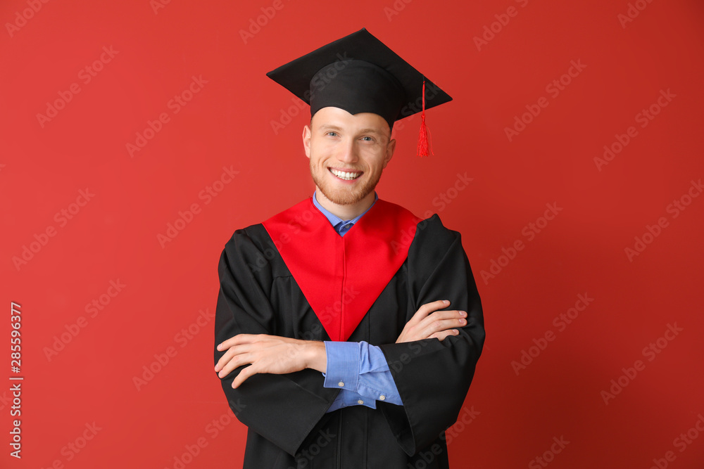 Young male student in bachelor robe on color background