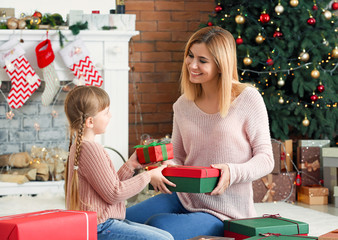 Wall Mural - Cute little girl and her mother with Christmas gifts at home