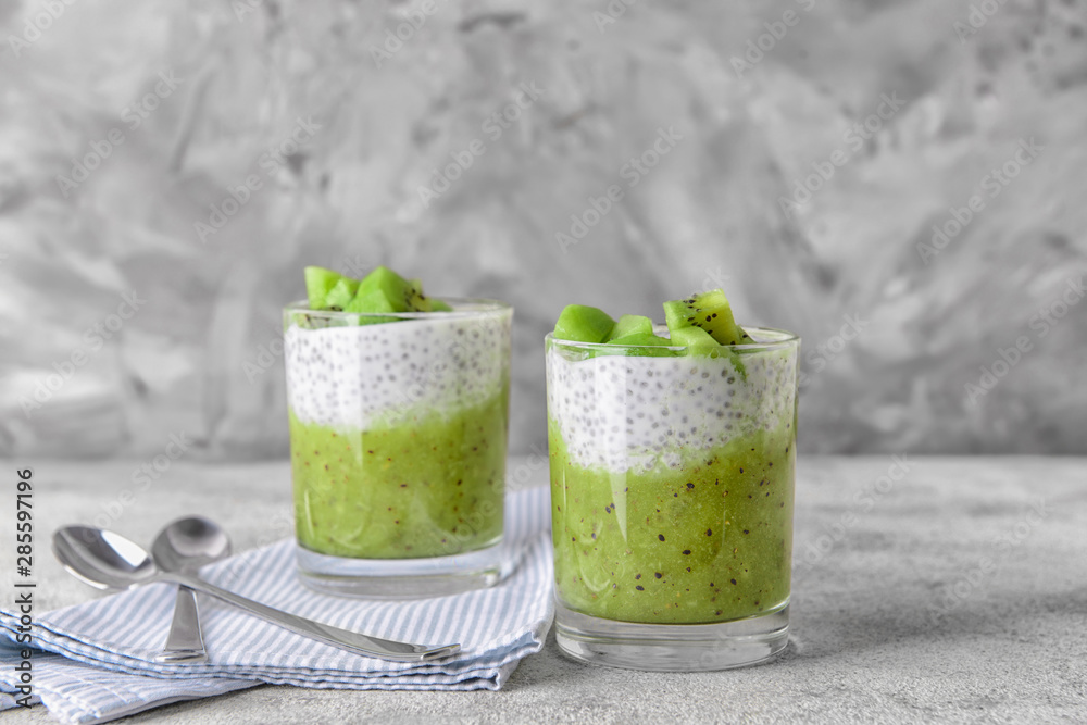 Glasses with tasty kiwi dessert on grey background