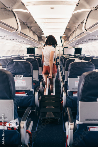 Fotografía Back view of young woman walking the aisle on plane