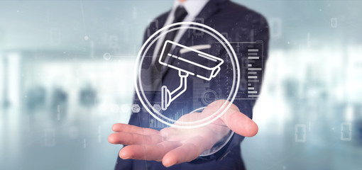 Poster - Businessman holding Security camera system icon and statistics data - 3d rendering