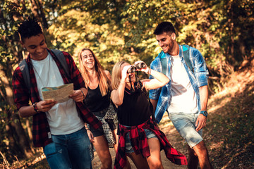 Wall Mural - Group of four friends having fun hiking through forest together.