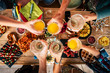 © simona - Group of friend mixed ages  generations from children to adult have fun togeter with food and drinks - aerial top view of table and people toasting together in friendship - home or restaurant concept