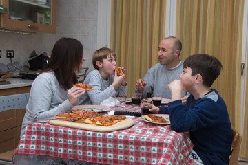 Wall Mural - Family of Four People Eating Pizza on the Kitchen Table at Home