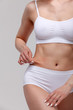 © Nobilior - Woman pinches fat on her belly, closeup shot.