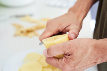 Wall Mural - man cutting thin slices of potato