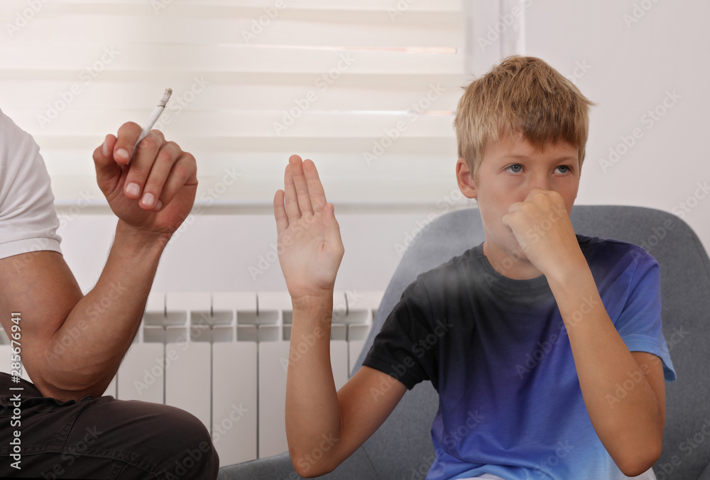 Stop smoking near children. Father smoking cigarette , boy disgusted by  smoke Stock Photo