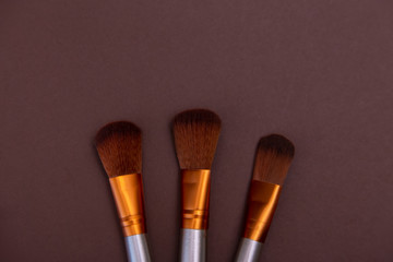 cosmetic makeup brushes on a brown background Copy space Cosmetic beauty concept