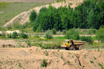 Poster - Big yellow dump truck transporting stone and gravel in an sand open-pit. Mining quarry for the production of crushed stone, sand and gravel for use in the construction industry - image