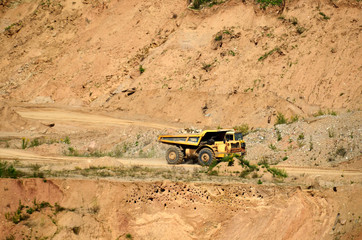 Poster - Big yellow dump truck works in an sand open-pit. Mining quarry for the production of crushed stone, sand and gravel for use in the construction industry - image