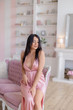 © fotoplaton - Young sexy brunette in a bright dress on a pink sofa
