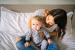 © Louis-Paul Photo - Mother and child on a white bed playing in sunny bedroom