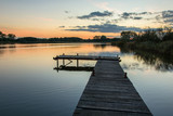 Fototapeta Pomosty - A pier on a calm lake and the sky after sunset