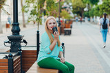 Fototapeta Przestrzenne - Portrait happy smile beautiful elegant woman blue blouse sitting on a bench and holding a paper cup of coffee